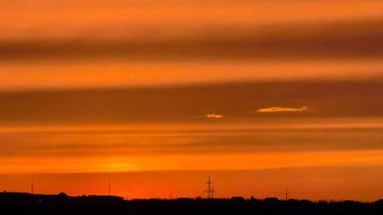Obraz premium Orange sunset sky over horizon with silhouettes and clouds