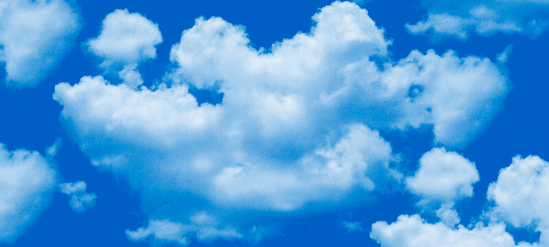 Beautiful cloudscape with soft white clouds over vivid blue background representing serenity and freedom during daytime in nature with bright sunlight illuminating the atmosphere and weather patterns