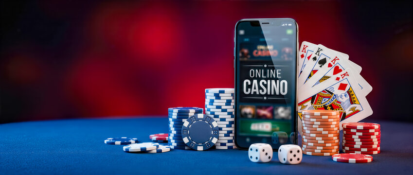 Smartphone displaying online casino game interface surrounded by colorful poker chips, playing cards, and dice on a blue table with a blurred background