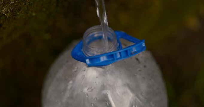 clean spring water flowing from a natural pipe into a reusable bottle, highlighting themes of ecology. travel content, or educational materials, this footage combines aesthetic beauty 