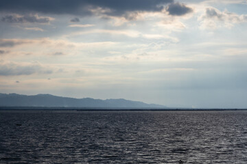 Fototapeta premium Calm Water With Distant Mountains Under Cloudy Sky
