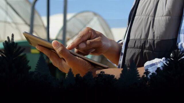 Man tapping and swiping tablet near greenhouse, showing animated crop charts and adjusting controls