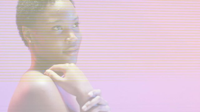Model posing on pink backdrop, adjusting hands, lines sweeping left, obscuring face for portrait