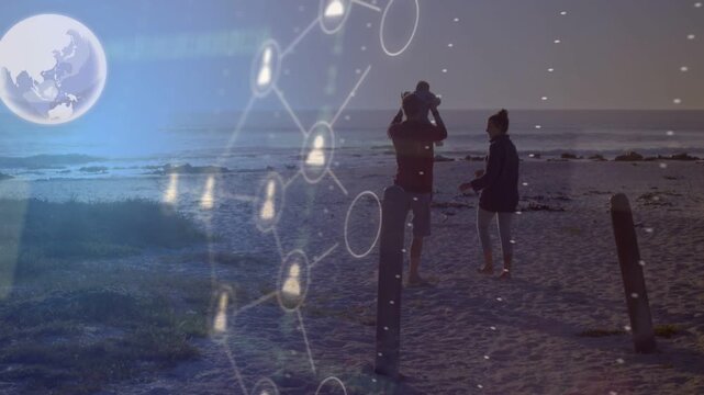Parents walking beach with baby on shoulders, passing phone causing tech profiles linking family