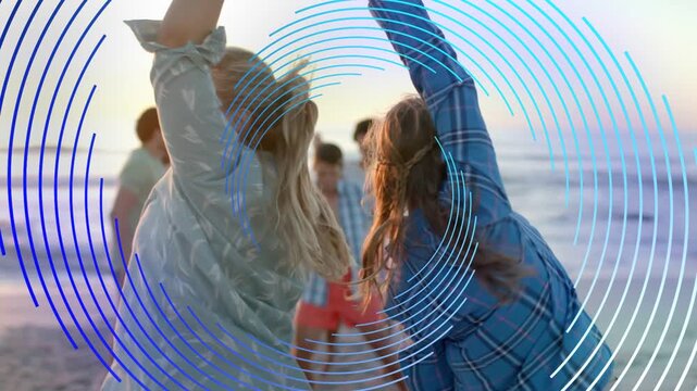 Two women raising hands, spinning on beach at sunset, concentric rings pulsing over scene for ads