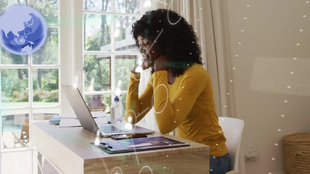 Woman working at desk, globe appearing initiating avatars clustering over laptop for remote meeting