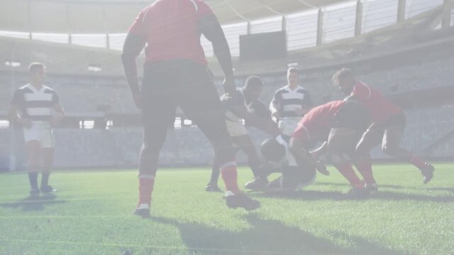 Striped ball carrier getting tackled on rugby pitch, red defenders forming ruck to secure ball