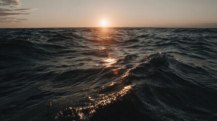 Obraz premium Brilliant sunlight reflects upon dark, restless ocean waves during twilight.