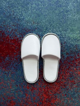 White cotton hotel slipper. A pair of clean, white disposable spa slippers placed on a hotel room floor, symbolizing hospitality, luxury, and comfort. Sendal kamar
