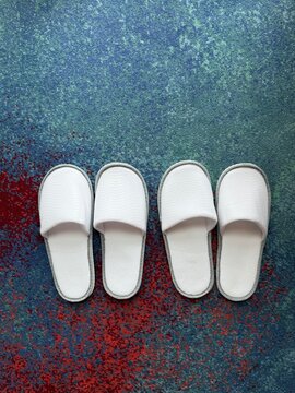 Two pairs of white citton slipper.  white disposable spa slippers placed on a hotel room floor, symbolizing hospitality, luxury, and comfort. Sendal kamar
