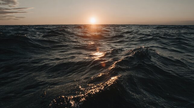 Brilliant sunlight reflects upon dark, restless ocean waves during twilight.