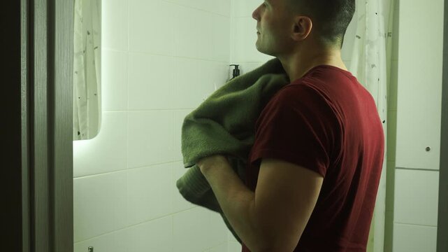 Morning routine. A man washes his face in front of a mirror.