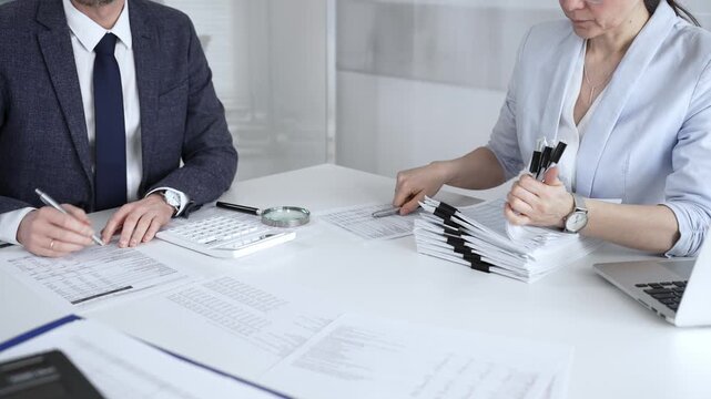 Professional accountant team analyzing corporate financial data, managing paperwork, and preparing tax reports, collaborating on bookkeeping and auditing tasks at a desk. Audit and taxes