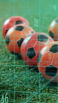 Vertical video: Row orange black soccer balls staying while camera pulling back and grid measuring
