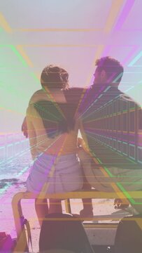 Vertical video: Left person pointing toward ocean, partner turning, tunnel wrapping cart for travel