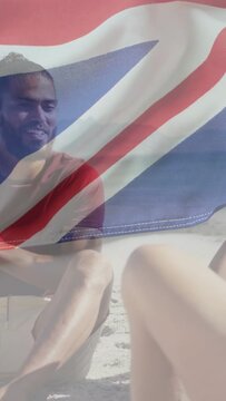 Vertical video: Man smiling at friend joke on beach, wind drifting sheer flag across lens marketing