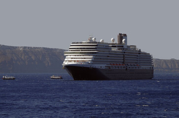 Luxury cruiseship cruise ship liner Eurodam anchoring at sea on sunny summer day during Mediterranean Greek Island Santorini caldera cruising with shore and rocky island in background © Tamme Wichmann