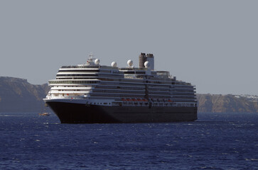 Luxury cruiseship cruise ship liner Eurodam anchoring at sea on sunny summer day during Mediterranean Greek Island Santorini caldera cruising with shore and rocky island in background © Tamme Wichmann