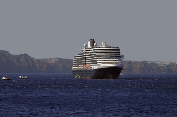 Luxury cruiseship cruise ship liner Eurodam anchoring at sea on sunny summer day during Mediterranean Greek Island Santorini caldera cruising with shore and rocky island in background © Tamme Wichmann