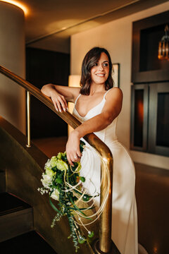 Bride posing on staircase holding wedding bouquet