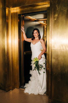 Bride in white dress exiting golden elevator