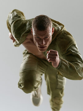 Dynamic action shot of a male runner in olive green technical gear, urban sport and speed concept