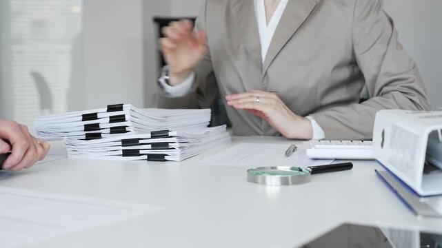 Professionals handling a large stack of documents and paperwork, signing a contract in a busy office. Audit and taxes in business