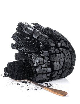 A pile of crushed black charcoal with a copper spoon