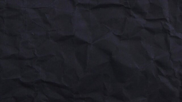 Crumpled black paper texture background with wrinkled folds and creases