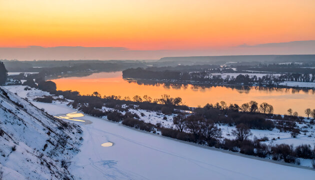 Beautiful landscape photograph showing a frozen river flowing through a snowy valley under a warm sunrise sky with serene reflections generative AI