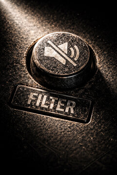 Muted control button on dusty equipment with filter label silent control power not speaking in moody macro shot evoking solitude and industrial silence