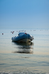 Obraz premium A boat in a calm sea near the shore at dawn