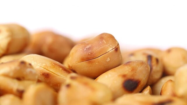 Pile of roasted hulled peanuts rotating slowly on white background. close-up view 

