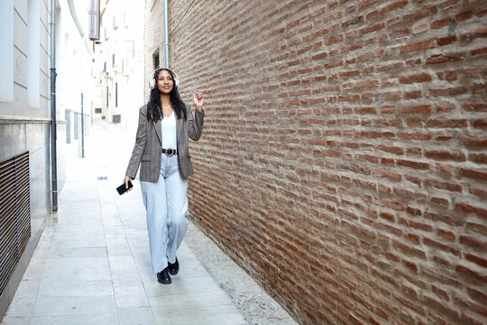 Trendsetting woman casually posing amidst historic brick surroundings under bright sunlight