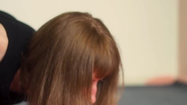 Close up of a woman in black top practicing deep shoulder and arms stretching and chest opening on yoga mat focusing on upper body flexibility thoracic mobility and stress relief exercise