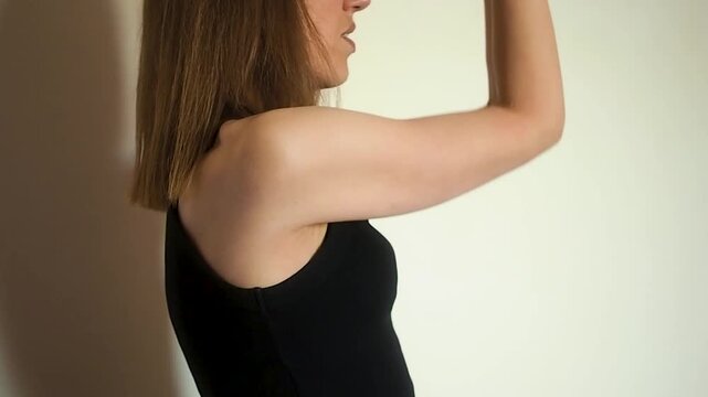 Horizontal video of fit woman in black top practicing shoulder mobility and arm stretching exercises at home athletic girl focusing on upper body flexibility for healthy posture and wellness