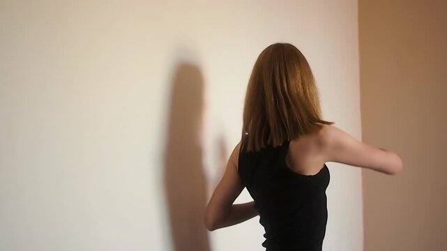 Нorizontal video of athletic woman in black sportswear practicing wall stretching and shoulder mobility exercises, focusing on chest opening and flexibility for healthy posture and wellness