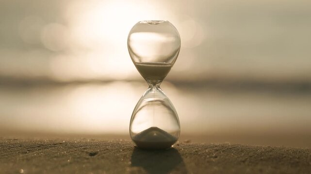 Close-up of glass hourglass on tropical beach at sunset symbolizing time, patience and the passage of life. Relaxing seaside background with soft golden reflections and calm ocean mood.