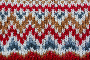 Obraz premium Traditional knitted pattern texture with red white and brown ornament, wool fabric close up