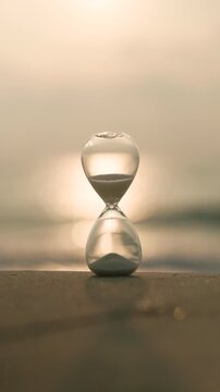 Glass hourglass on a sandy shore glowing in golden sunlight, representing time, waiting, deadlines, change, reflection, and the precious balance between past, present, and future.