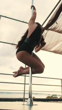 Young beautiful girl dancer with flowing hair rotated around pole - dance outdoor