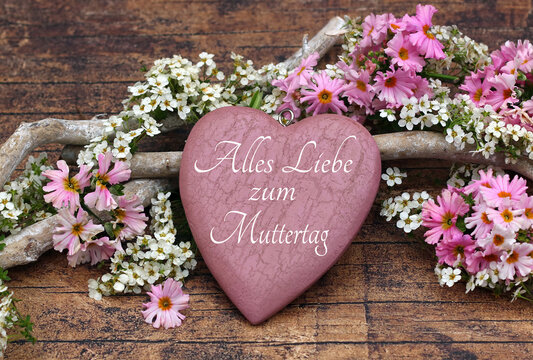Rustikale Gl&uuml;ckw&uuml;nsche zum Muttertag &ndash; Herz mit der Beschriftung Alles Liebe zum Muttertag mit Bl&uuml;ten und Treibholz auf Holzhintergrund.