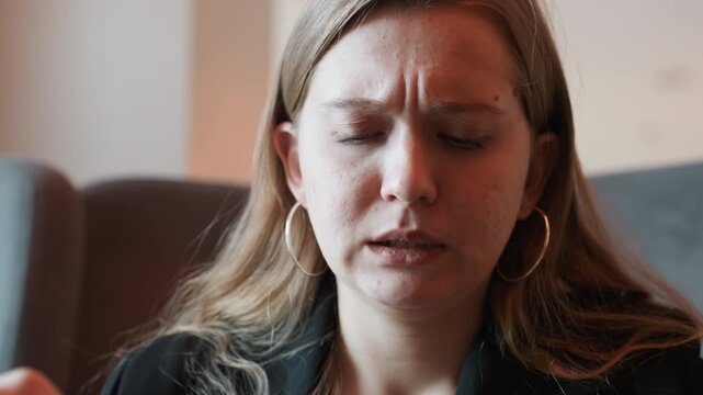 Woman shows frustration over bitter taste. Woman reacts negatively to unpleasant biting sensation indoors. Indoor scene captures woman with furrowed brow and hand on forehead expressing discomfort