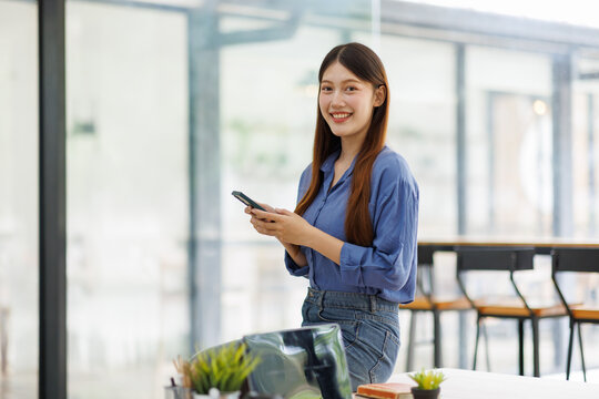 Smiling woman using smartphone in modern office