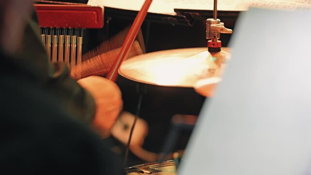 Musician playing a drum kit on the drumstick, performing live at a jazz concert. A dynamic over-the-shoulder view of a musician playing drums at a concert. Drumsticks strike cymbals