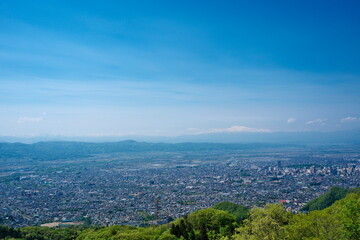 Fototapeta premium Panoramic view of a Japanese city in a valley with snow capped mountains in the distance