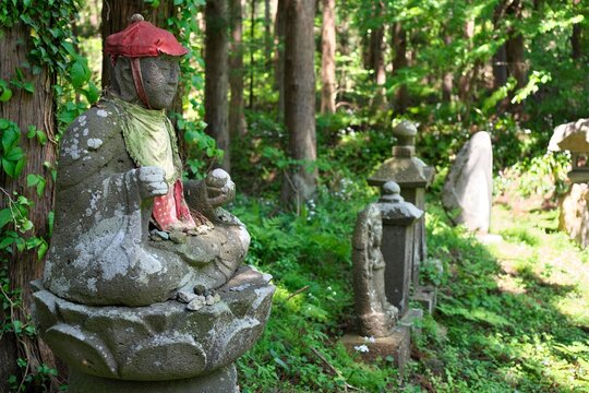 Traditional stone Jizo statues with red hats in a peaceful Japanese forest
