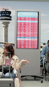 Vertical video Multiethnic crowd in airport waiting for departure gate to open after global disruption delays flights. Tourists upset by cancelled international flight in air transportation transit