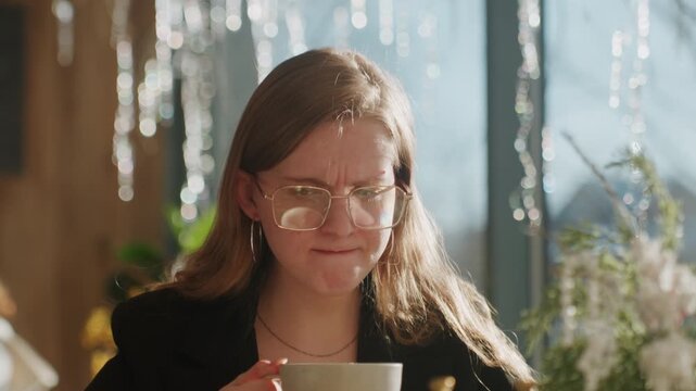 Woman tastes bitter coffee. Woman from Caucasus makes faces when tasting extremely bitter hot beverage. Caucasian female grimaces and squints as she experiences intense bitterness of hot coffee