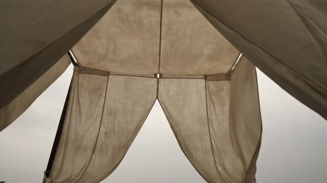 Low angle view inside of a light canvas tent with the opening against a cloudy sky